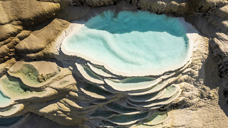 Endapan mineral putih yang ditangkap di kolam bertingkat yang dibentuk oleh air kaya kalsium yang berasal dari mata air di bawahnya menciptakan fenomena alam yang magis dan mengesankan